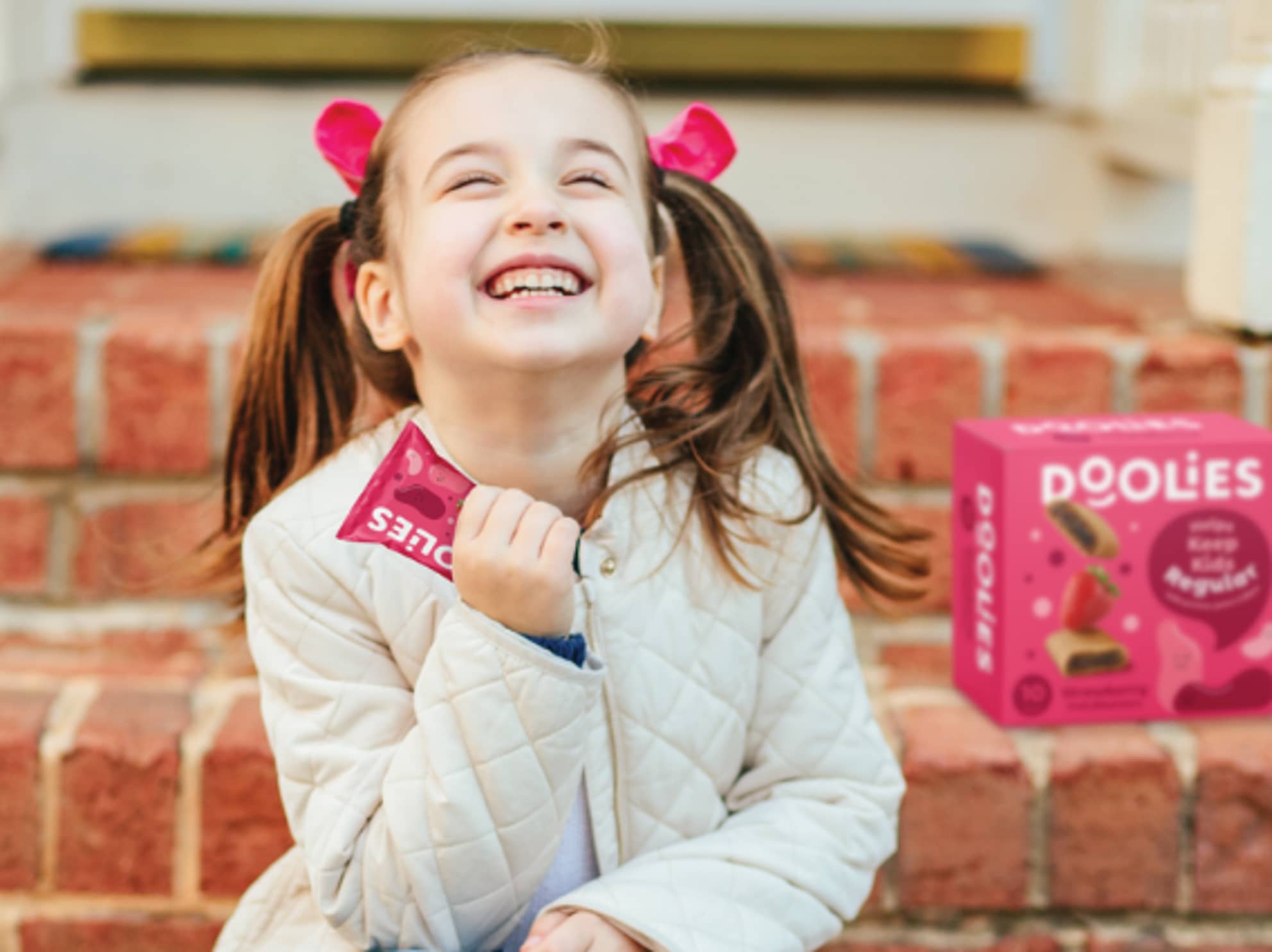 Girl with pig tails holding a Doolies bar and looking up smiling